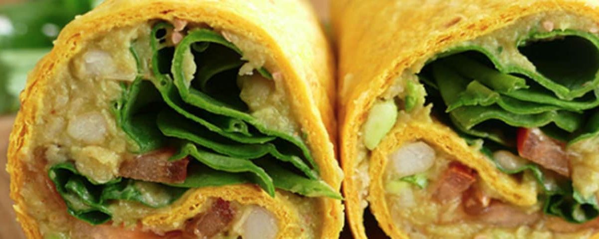 Wrap met bonen, avocado en spinazie, opgerold met tomaat en koriander – vezel- en eiwitrijke lunch to-go.