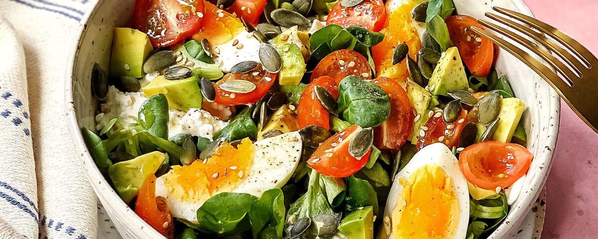 Salade in kom met veldsla, avocado-stukken, partjes ei, kerstomaatjes en cottage cheese – fris en voedzaam, snel op tafel.