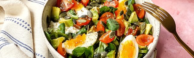 Salade in kom met veldsla, avocado-stukken, partjes ei, kerstomaatjes en cottage cheese – fris en voedzaam, snel op tafel.