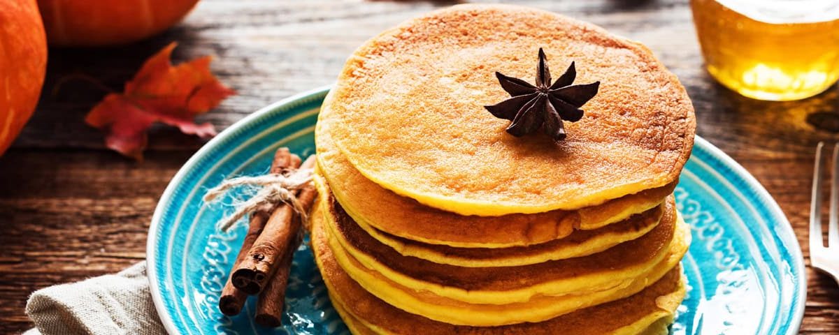 Pompoen-pannenkoeken met kaneel en yoghurt op een bord – gezond herfstontbijt.