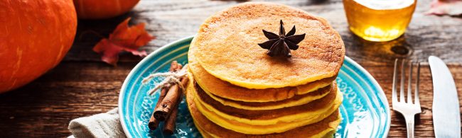 Pompoen-pannenkoeken met kaneel en yoghurt op een bord – gezond herfstontbijt.