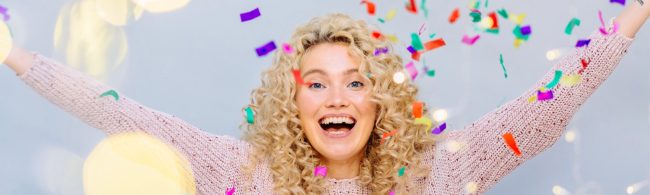Vrouw juicht met vallende confetti — nieuwjaar en goede voornemens, feestelijke start van gezonde doelen.
