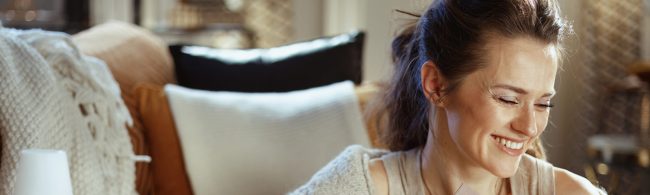 Vrouw lacht in huiselijke setting; wellness/gezondheidssfeer passend bij hormoonbalans-artikel.