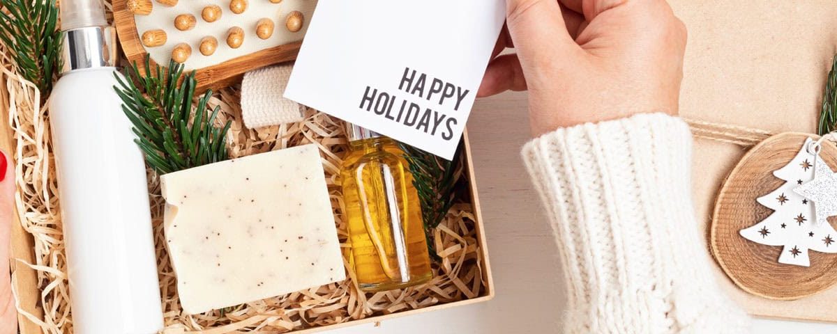 Feestelijk ingepakte kerstcadeaus op tafel met dennetakken en lichtjes — inspiratie voor gezonde kerstcadeaus (wellness, koken, bewegen).