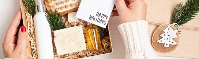 Feestelijk ingepakte kerstcadeaus op tafel met dennetakken en lichtjes — inspiratie voor gezonde kerstcadeaus (wellness, koken, bewegen).