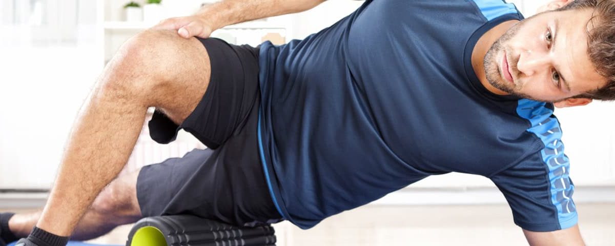 Persoon foamrollt de dij/fascia met fitnessroller, gericht op zelfzorg voor soepel bindweefsel.