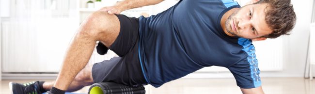 Persoon foamrollt de dij/fascia met fitnessroller, gericht op zelfzorg voor soepel bindweefsel.