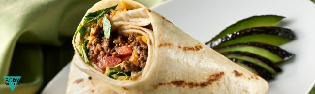 Gezonde fastfood wrap met mager rundergehakt, ijsbergsla, tomaat, augurk, ui en gesmolten kaas op volkoren wrap – gezonder alternatief voor een burger.