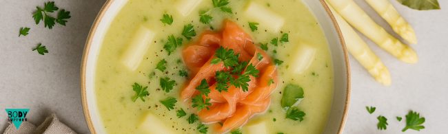 Kom met gezonde aspergesoep, romig en licht, gegarneerd met groene aspergetips.