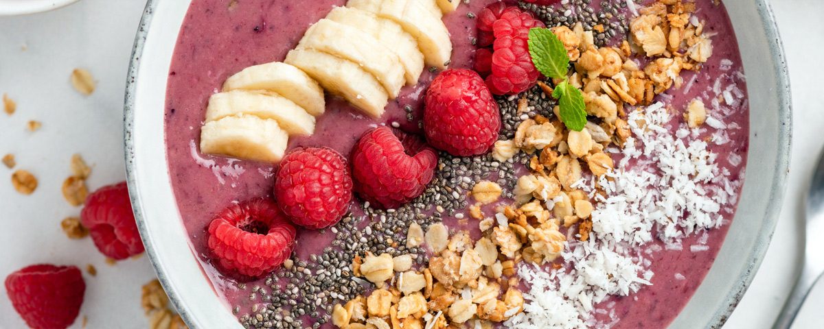 Zomerse smoothie bowl met framboos en kokos, geserveerd met frisse toppings.